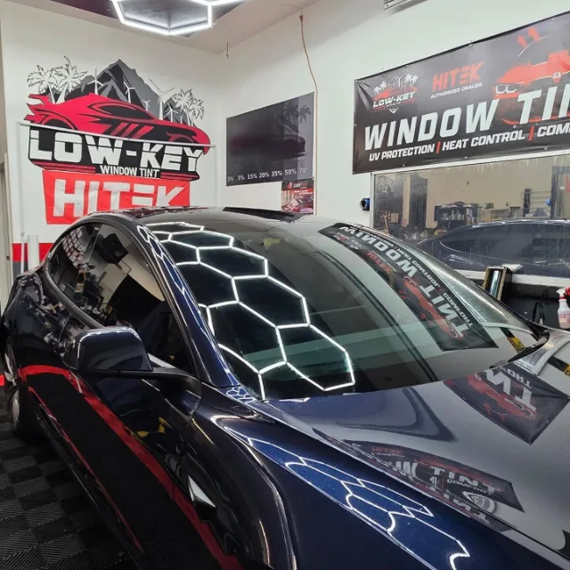 Blue Tesla Model 3 windshield and driver-side windows inside the Lowkey shop